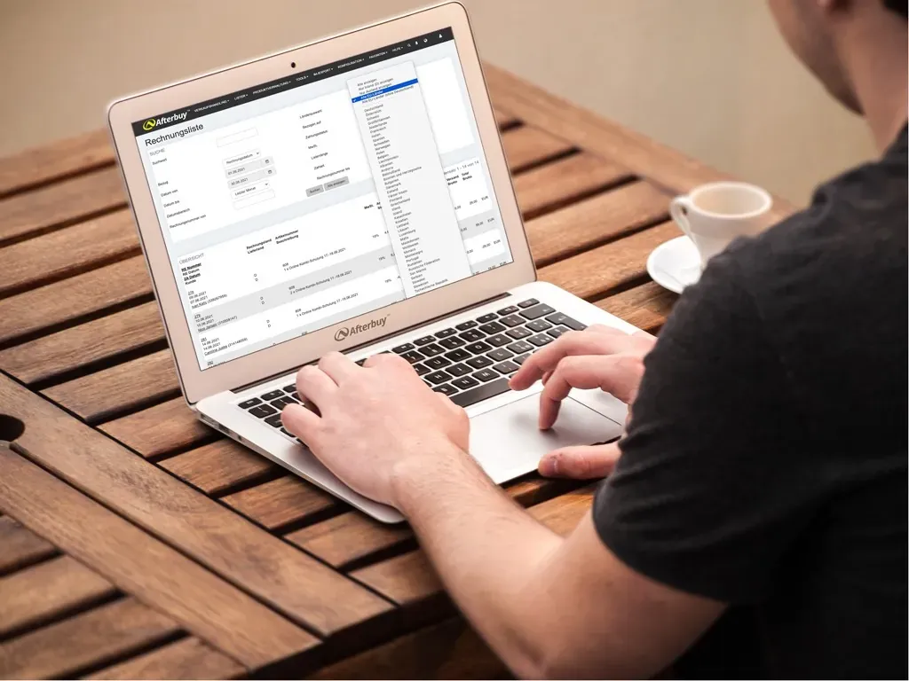 Eine Person benutzt einen Laptop auf einem Holztisch, auf dessen Bildschirm die Benutzeroberfläche von ECOMMERCE ONE mit Form