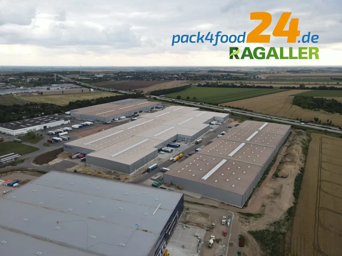 Luftaufnahme eines großen Industriekomplexes in Magdeburg mit mehreren Lagerhallen, die von Feldern umgeben sind. Das Logo „p