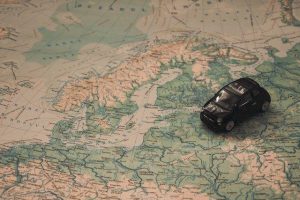 Ein kleines schwarzes Spielzeugauto steht auf einer Karte, die über der skandinavischen Region in Nordeuropa, einschließlich Norwegen, Schweden und Finnland, positioniert ist. Die Karte zeigt die umliegenden Länder und Gewässer.