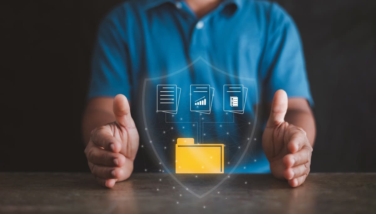 Ein Mann hält einen gelben Ordner mit einem Schild darauf, der IT-Sicherheit und KMU repräsentiert.