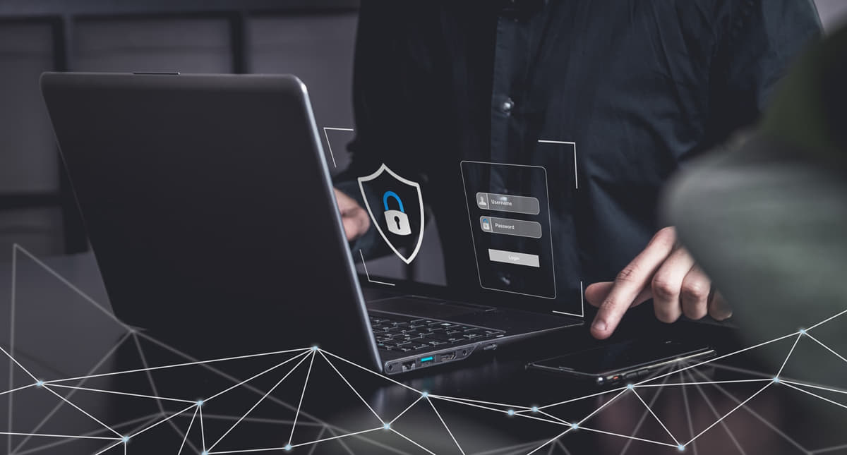 Ein Mann nutzt einen Laptop mit Sicherheitsschild, um die IT-Sicherheit und den Datenschutz von KMU zu gewährleisten.