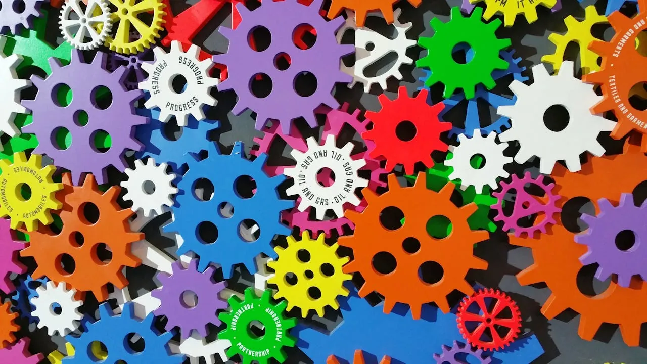 Bunte Zahnräder in verschiedenen Größen und Farben, darunter Lila, Grün, Orange, Weiß und Blau, sind vor einem dunklen Hintergrund ineinander verzahnt. Auf einigen Zahnrädern ist Text zum Thema E-Commerce aufgedruckt. Das Muster ist komplex und optisch lebendig.
