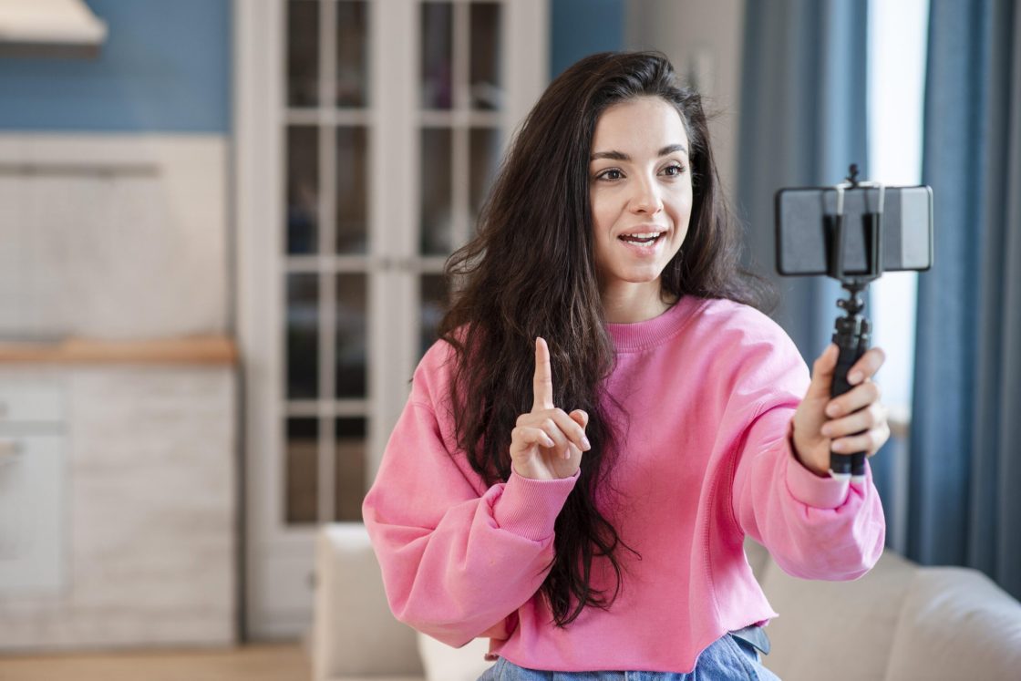 young-blogger-using-selfie-stick-talking-phone-scaled